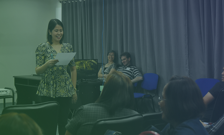 Woman reading a piece of paper in front of her audience