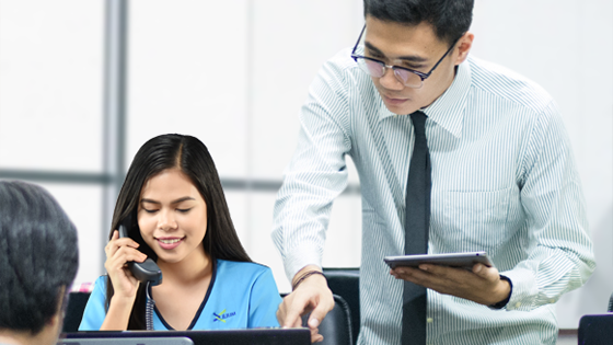 A virtual assistant answering a phone call, beside her is a man holding a tablet